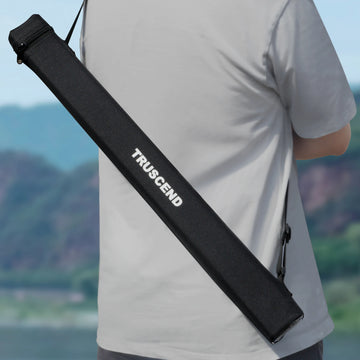Person holding a black TRUSCEND fishing rod case with a scenic background